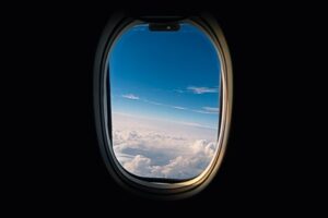 Utsikt fra et flyvindu over skyer og blå himmel