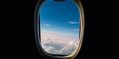 Utsikt fra et flyvindu over skyer og blå himmel