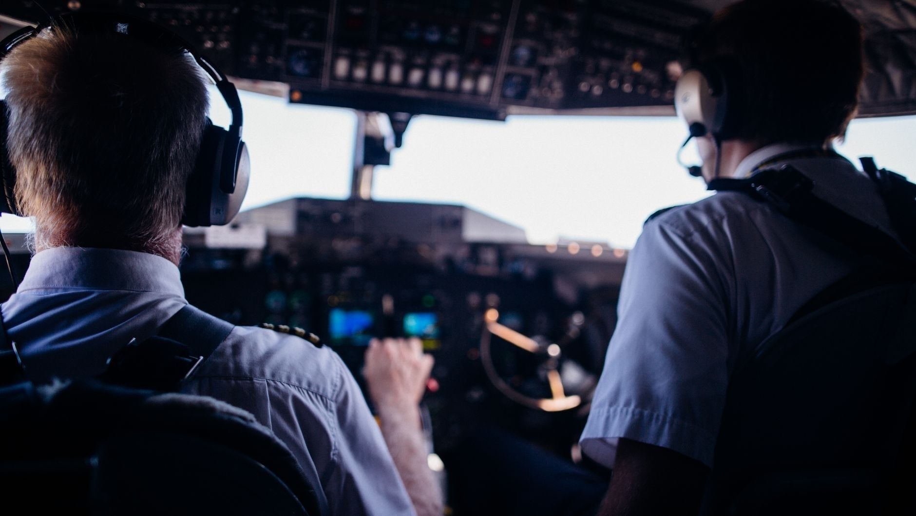 To piloter i uniform arbeider ved instrumentene i en cockpit