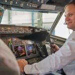 Pilot med headset betjener instrumentene i cockpit under flyging