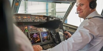 Pilot med headset betjener instrumentene i cockpit under flyging