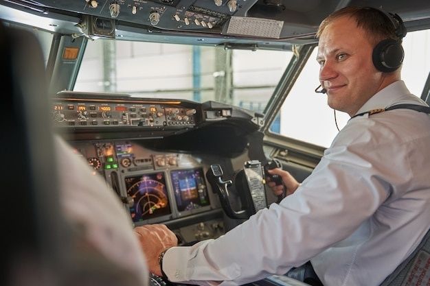 Pilot med headset betjener instrumentene i cockpit under flyging